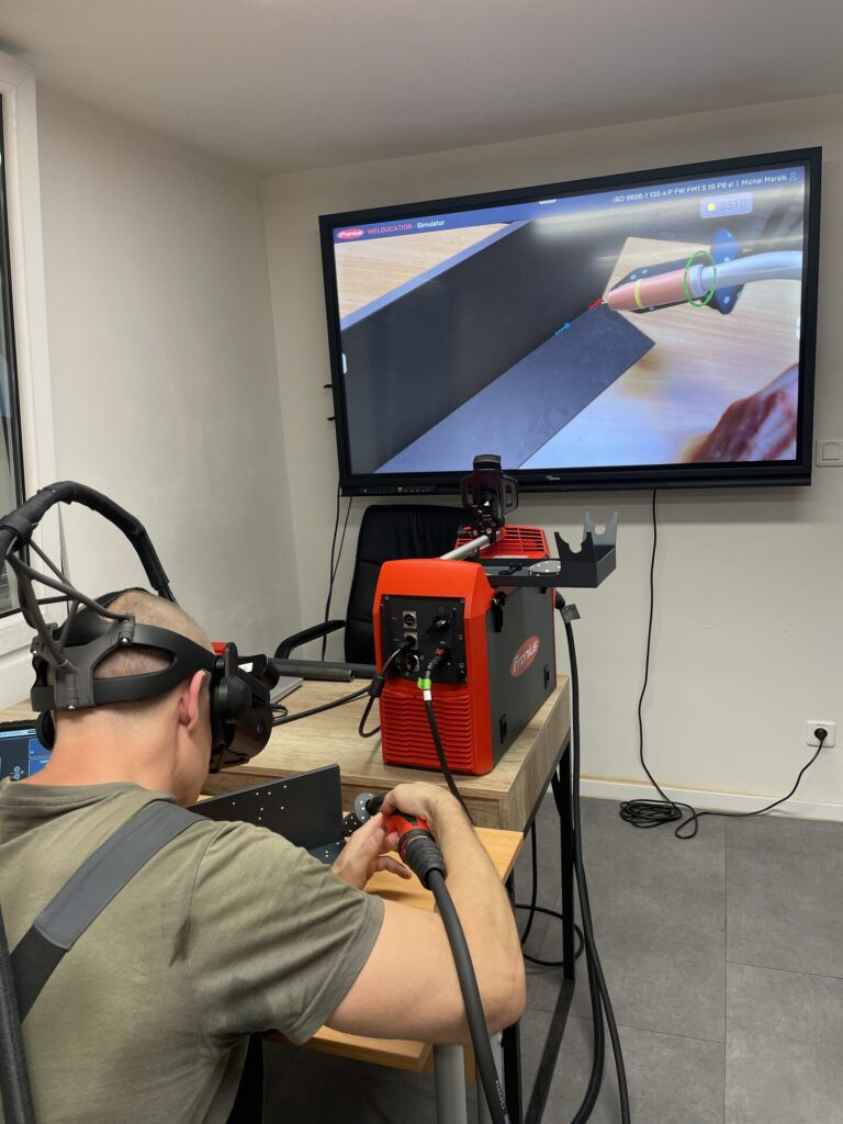 Účastník svařuje na simulátoru ve virtuální realitě, na obrazovce je vidět svar